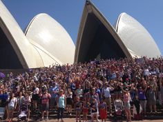 a large group of people standing in front of the sydney opera house