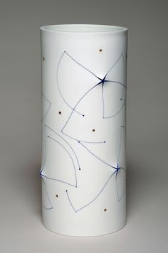 a white vase with blue lines and dots on the inside is shown in front of a gray background