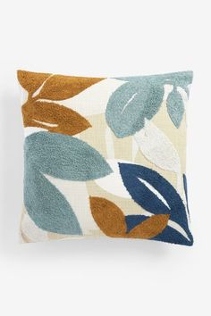 a blue and brown pillow with leaves printed on it's side, against a white background