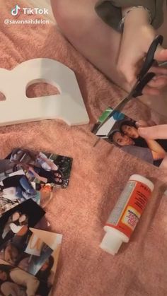 a person cutting up pictures with scissors on a bed next to a white mask and other items