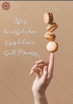 a woman's hand holding three macaroons on top of each other with the words life is beautiful when its in balance good morning