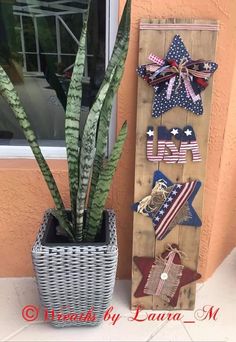 a potted plant sitting next to a wooden sign with stars and stripes on it