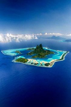 an island in the middle of the ocean surrounded by land and water with blue skies