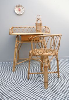 a table and chair made out of rattan with a basket on the top, against a gray wall