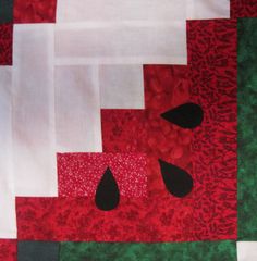 a red and green patchwork quilt with black tears on the center, along with white strips