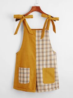 a brown and white checkered dress hanging on a wooden hanger with a yellow bow