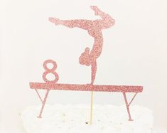 a pink cake with a figure on top and the number eight in the middle is standing on a table