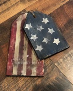 two wooden tags with the american flag painted on them are sitting on a wood floor