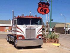 a red and white semi truck parked in front of a gas station with a phillips 66 sign