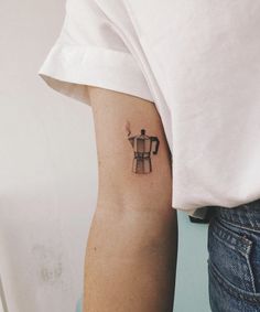 a person with a tattoo on their arm holding a coffee pot in one hand and a cup in the other