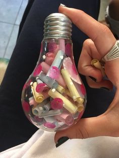 a person holding a light bulb filled with small objects
