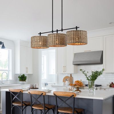 This farmhouse-style linear island chandelier light features matte black hardware and 3 drum shades which are meticulously hand-woven of natural rattan/wicker, making it a unique hanging pendant light for above the kitchen island and dining table or cafe bar. This collection can work with a variety of boho decors and even work in homes with coastal or farmhouse styling | Bay Isle Home™ Lannister 3 - Light Kitchen Island Drum Chandelier Metal in Brown | 10.4 H x 41 W x 11 D in | Wayfair Kitchen Island And Dining Table, Island And Dining Table, Farmhouse Chandelier Lighting, Lights Over Kitchen Island, Island Light Fixtures, Kitchen Island Chandelier, Island Chandelier, Kitchen Chandelier, Light Kitchen Island