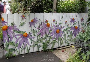 Purple echinacea painted on this white fence allude to the amazing garden within