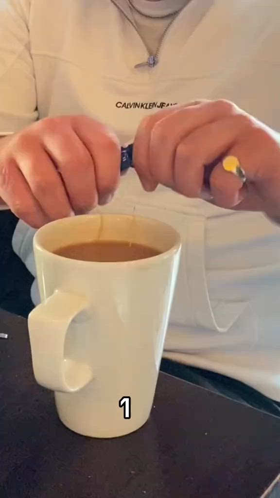 This may contain: a man sitting at a table with a cup of coffee