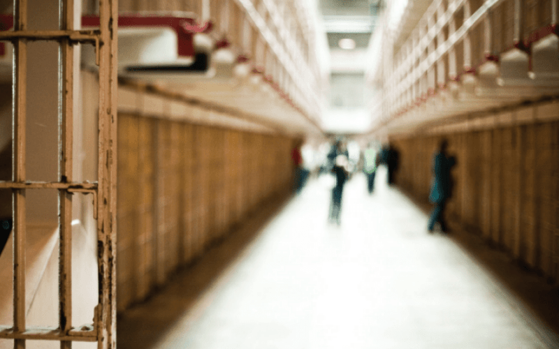 The interior of a jail. A jail cell door swinging open.