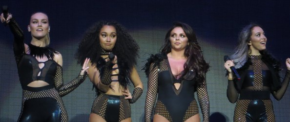 The four members of the girl band Little Mix on stage, all wearing black fishnet clothing.