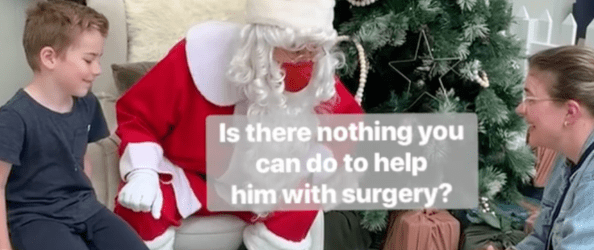 A white boy sits on a stall next to Santa, who is leaning forward to speak to a white mum, who is kneeling. Text captioning speech from Santa reads: "Is there nothing you can do to help him with surgery?"