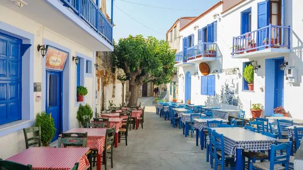 Typical Greece square in an ancient town Alonissos with typical exterior with blue doors and blue fence.