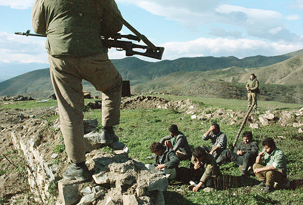 Боец с винтовкой охраняет задержанных армян.