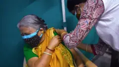 A woman receives a dose of COVISHIELD, a coronavirus disease (COVID-19) vaccine at a Kolkata Municipality medical centre in Kolkata.