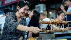 一名婦女在中國的戶外燒烤攤上燒烤食物