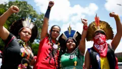 Four indigenous women raise their hands as they call for gender equality during a protest in Brasilia on International Women's Day, on March 8, 2020.