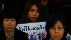 A woman holding a sign saying no means no