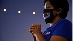 A democratic supporter with her hands clasped in prayer watches Senator Kamala Harris speaking in Las Vegas