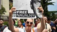 Протестующая с плакатом "Free Navalny" (освободите Навального).)