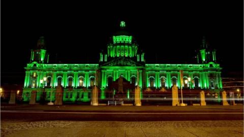 Belfast City Hall lit up with green lights
