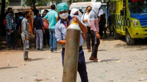 A healthcare worker holds an oxygen canister in Delhi