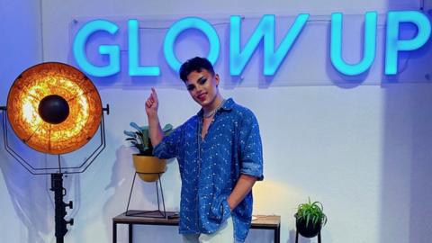 Wezley Webber in front of the neon Glow Up sign
