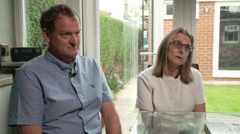 Nigel, wearing a blue short-sleeved shirt, and Julie, wearing a white top