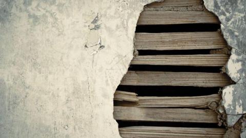 Close up of lath and plaster showing strips of wood behind broken plaster