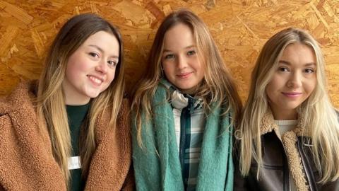 Daisy Hobman, Isabella Spicer, Isobel Cattle sitting down wearing scarfs