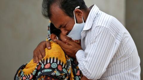 A woman is consoled by a relative outside a hospital in Ahmedabad, India, after her husband died from the coronavirus disease