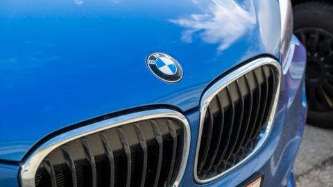 The hood of a blue BMW car with the logo visible.