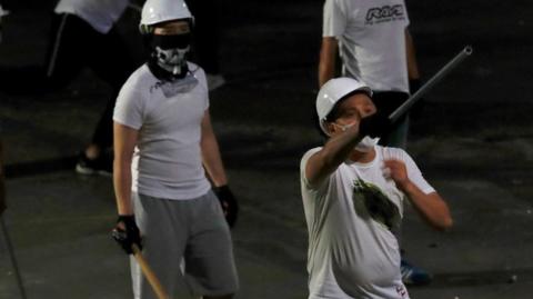 Men in white T-shirts with poles are seen in Yuen Long after attacked anti-extradition bill demonstrators at a train station, in Hong Kong, China July 22, 2019.