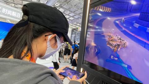 A visitor plays a mobile game at the booth of Tencent in Beijing, China.