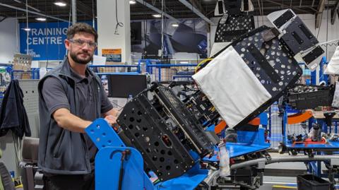 Eoin Murray, operations manager at Thompson Aero Seating, stands next to a jig holding a partly assembled airline seat