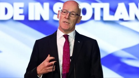 John Swinney delivering a speech