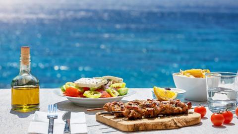 chicken skewers, salad and olive oil by the sea