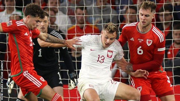 Szymon Zurkowski of Poland is challenged by Neco Williams and Joe Rodon of Wales