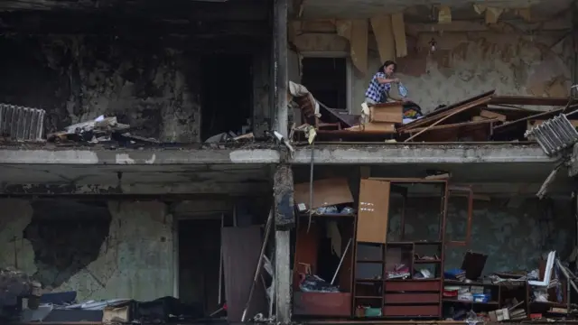 A woman collects belongings from her apartment in Kyiv