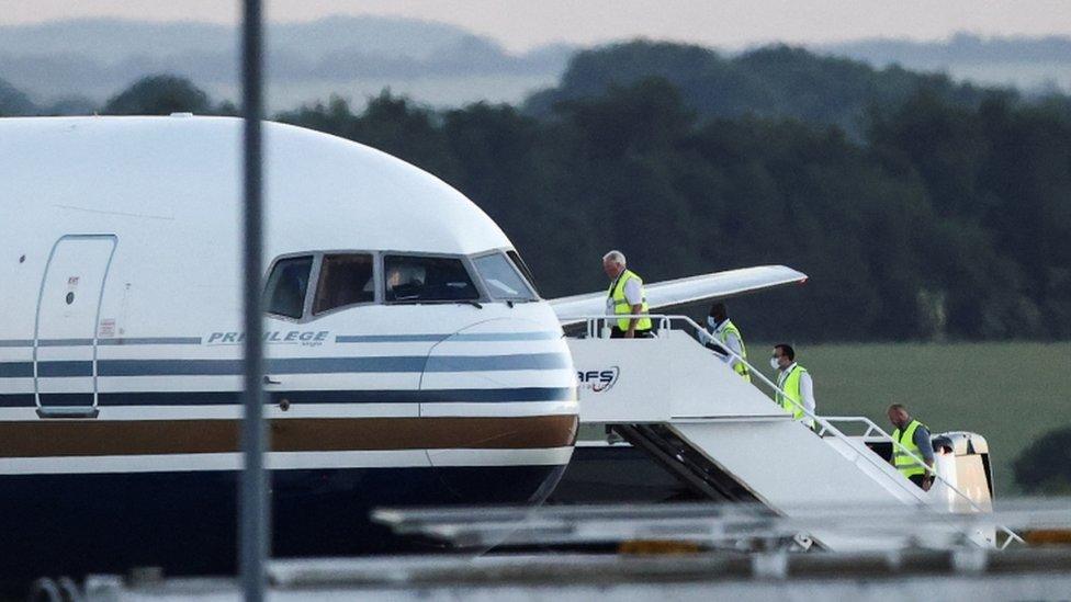 Members of the staff board a plane reported by British media to be first to transport migrants to Rwanda