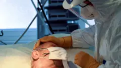 A medical staff member is seen next to a patient suffering from the coronavirus disease (COVID-19) in the intensive care unit at the Circolo hospital in Varese, Italy April 9, 2020.