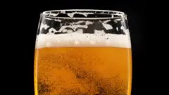 Стакан с пивом с пузырями на темном поле