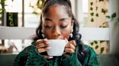 Woman dey drink coffee