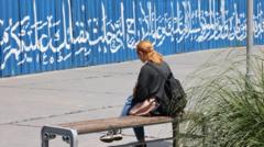 دختری بدون حجاب روی نیمکت نشسته