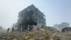 Two figures by a bombed-out building in Khan Younis